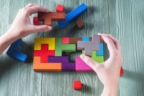 Hands arranging colourful puzzle blocks
